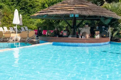 a swimming pool with a bar in a resort at Dionysos Hotel in Ixia