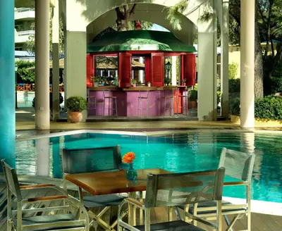 a table and chairs next to a swimming pool at Dionysos Hotel in Ixia
