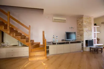 a living room with a staircase and a television at Serenity Sea-View Home in Afantou