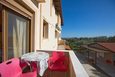 a patio with pink chairs and a table on a balcony at Serenity Sea-View Home in Afantou