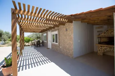 a wooden pergola with a table and chairs on a patio at Serenity Studio Beach Home in Afantou