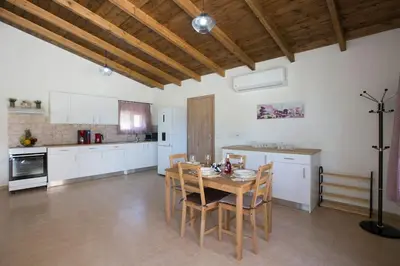 a large kitchen with a wooden table and chairs at Serenity Studio Beach Home in Afantou