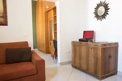 a living room with a couch and a laptop on a wooden cabinet at Niochori Heritage: The Pianist Suite in Rhodes Town