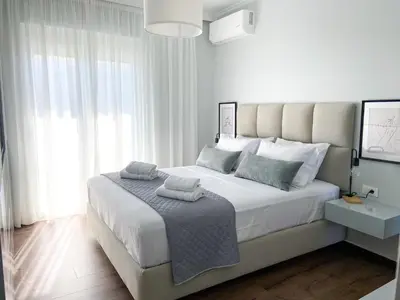 a white bedroom with a large bed with white curtains at SimplyCity Homestay Apartment 1 in Kremasti