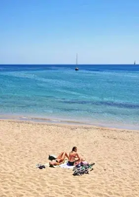 two people sitting on a towel on the beach at Melograno di Rodi 4 in Rhodes Town