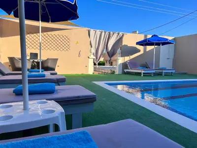 a pool with chairs and umbrellas next to a building at Villa Nektarina in Afantou