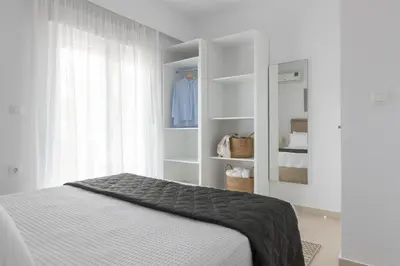 a white bedroom with a bed and a closet at Island Hills in Rhodes Town