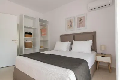 a white bedroom with a large bed with white pillows at Island Hills in Rhodes Town