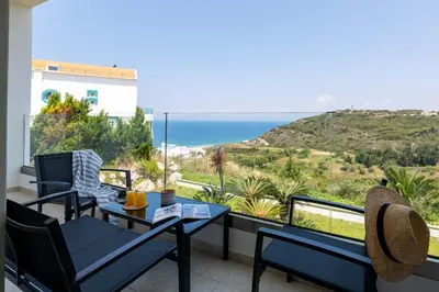 a balcony with a table and chairs and a view of the ocean at Island Hills in Rhodes Town