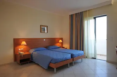 a bedroom with a bed with blue sheets and a window at Golden View Studios in Líndos