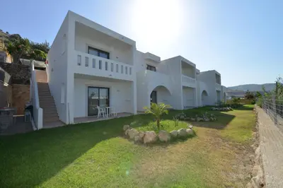 a large white house with a grass yard at Golden View Studios in Líndos