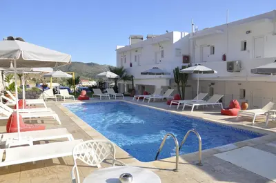 a swimming pool with chairs and umbrellas next to a building at Golden View Studios in Líndos