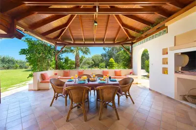 an outdoor dining room with a table and chairs at Villa Amelia in Gennadi