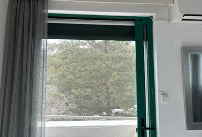 a window with a green curtain and a tree at Christos Apt - City Center w/ Royal Garden View in Rhodes Town