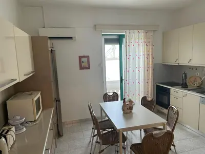 a kitchen with a white table and chairs and a kitchen with a window at Christos Apt - City Center w/ Royal Garden View in Rhodes Town