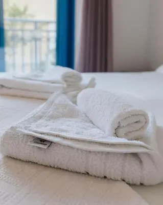 a pile of towels sitting on a bed at Hotel Nathalie in Ixia