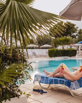 two women laying on chaises by a swimming pool at Hotel Nathalie in Ixia