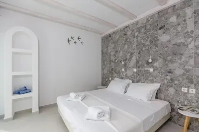 a bedroom with a white bed and a stone wall at Hotel Nathalie in Ixia