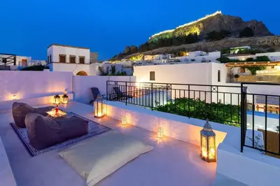 a patio with a couch and lights at night at Lindos Villa Petra with Acropolis View in Líndos
