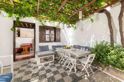 a patio with a table and chairs under a pergola at Lindos Villa Petra with Acropolis View in Líndos