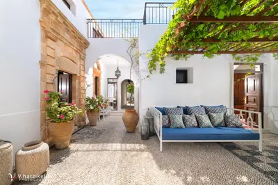 a patio with a blue couch in a building at Lindos Villa Petra with Acropolis View in Líndos