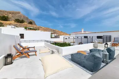 a patio with chairs and a couch on a roof at Lindos Villa Petra with Acropolis View in Líndos