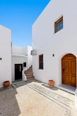 a white building with a wooden door and stairs at Pera houses 2-bedroom in the center of Lindos in Líndos