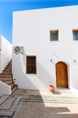 a white building with a wooden door and stairs at Pera houses 2-bedroom in the center of Lindos in Líndos
