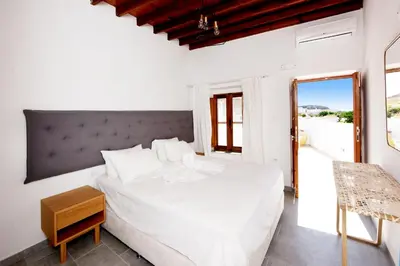 a white bedroom with a large bed and a window at Pera houses 2-bedroom in the center of Lindos in Líndos
