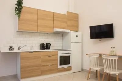 a kitchen with a white refrigerator and a table with chairs at Niochori Heritage: The Mermaid Suite in Rhodes Town