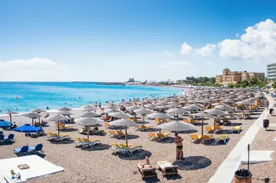 a beach with many chairs and umbrellas and the ocean at Niochori Heritage: The Mermaid Suite in Rhodes Town