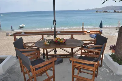 a table and chairs on a beach with the ocean at Maroulitsas Sea Esta 1 in Haraki
