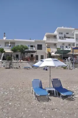 two chairs and an umbrella on a beach at Maroulitsas Sea Esta 1 in Haraki