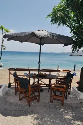 a table and chairs under an umbrella on the beach at Maroulitsas Sea Esta 2 in Haraki