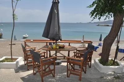 a table with chairs and an umbrella on the beach at Maroulitsas Sea Esta 2 in Haraki