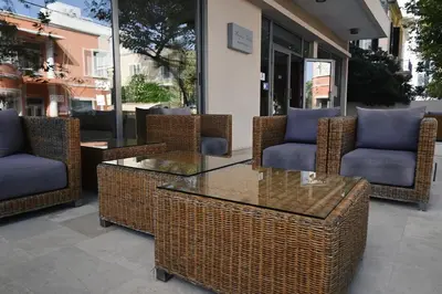 a patio with wicker chairs and a glass table at Angela Downtown Hotel in Rhodes Town