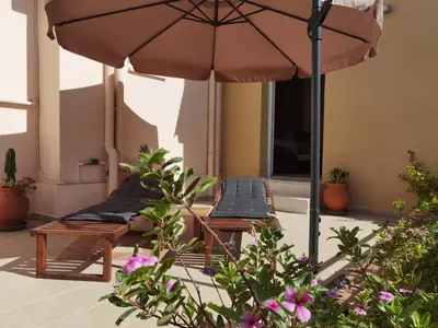 a patio with two lounge chairs and an umbrella at Beautiful apartment with 3 bedrooms in Archangelos