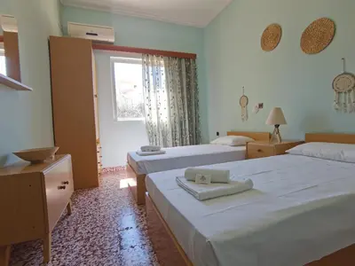 a hotel room with two beds and a window at Beautiful apartment with 3 bedrooms in Archangelos