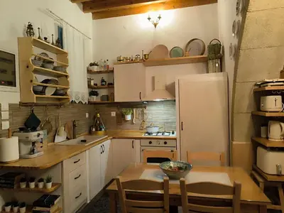 a kitchen with a table and a white refrigerator at Rustic House Archangelos in Archangelos