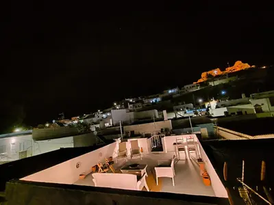 a view of a balcony at night with white chairs at Rustic House Archangelos in Archangelos