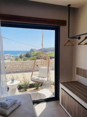 a room with a large window with a chair outside at Lithos Luxury Villa in Archangelos