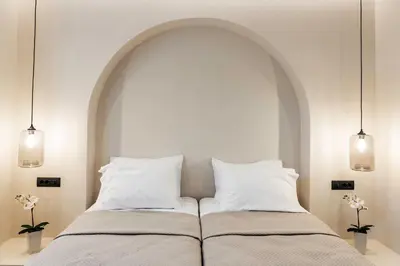 a bed with two pillows and an arch above it at Lithos Luxury Villa in Archangelos