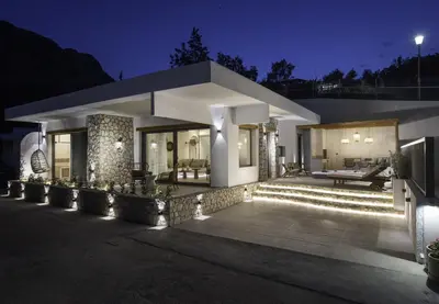 a modern house with a patio at night at Lithos Luxury Villa in Archangelos