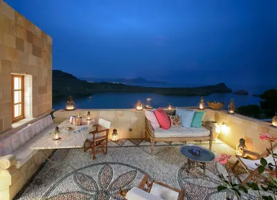 a patio with a couch and a table with lights at Melenos Art Boutique Hotel in Líndos