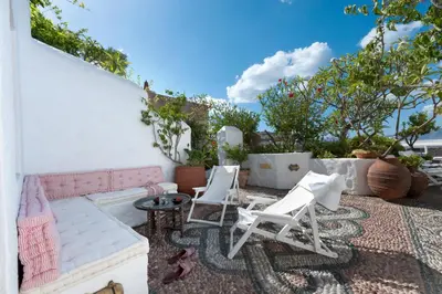 a patio with white chairs and a couch at Melenos Art Boutique Hotel in Líndos