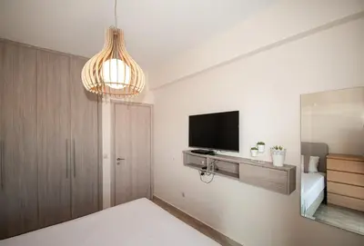 a living room with a television and a chandelier at Saint Francis Apartment in Rhodes Town