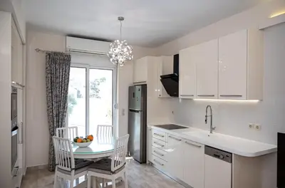 a kitchen with white cabinets and a table with chairs at Saint Francis Apartment in Rhodes Town