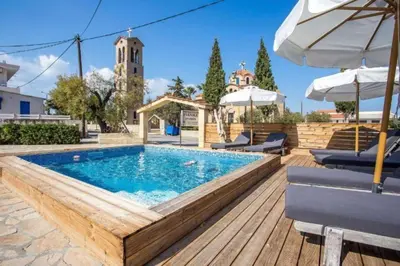 a pool with chairs and an umbrella on a wooden deck at Pagona Studios in Faliraki