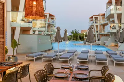 a patio with a table and chairs and a pool at Eden Roc Resort - All Inclusive in Kallithea Rhodes