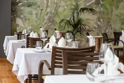 a dining room with white tables and chairs with wine glasses at Eden Roc Resort - All Inclusive in Kallithea Rhodes
